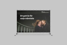 Stor vepa med bild på två leende kvinnor med ansiktena mot varandra. De ser förälskade ut. På bilden finns budskapet Ett gott liv för varje människa och VGR:s logotyp längst upp i högra hörnet