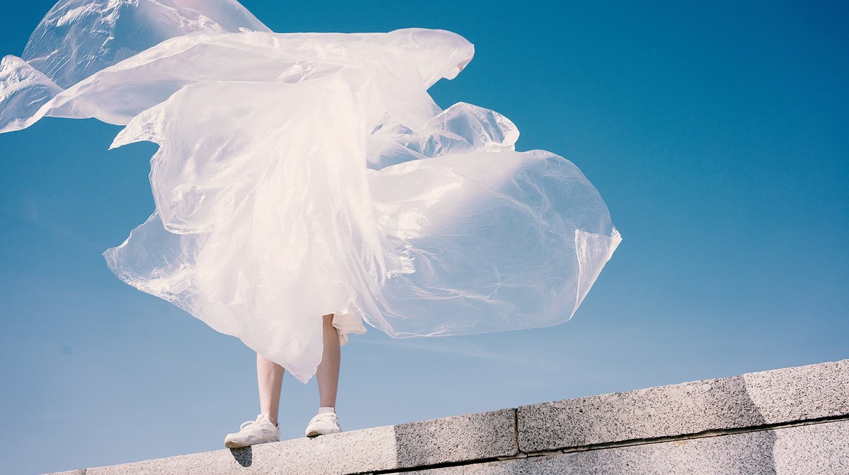 Person döljs bakom vit tyllkjol som avtecknar sig mot en blå himmel
