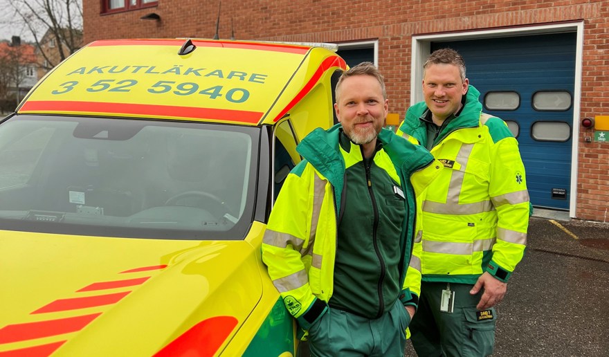 Akutläkare och ambulanssjuksköterska står vid sidan av en akutläkarbil.