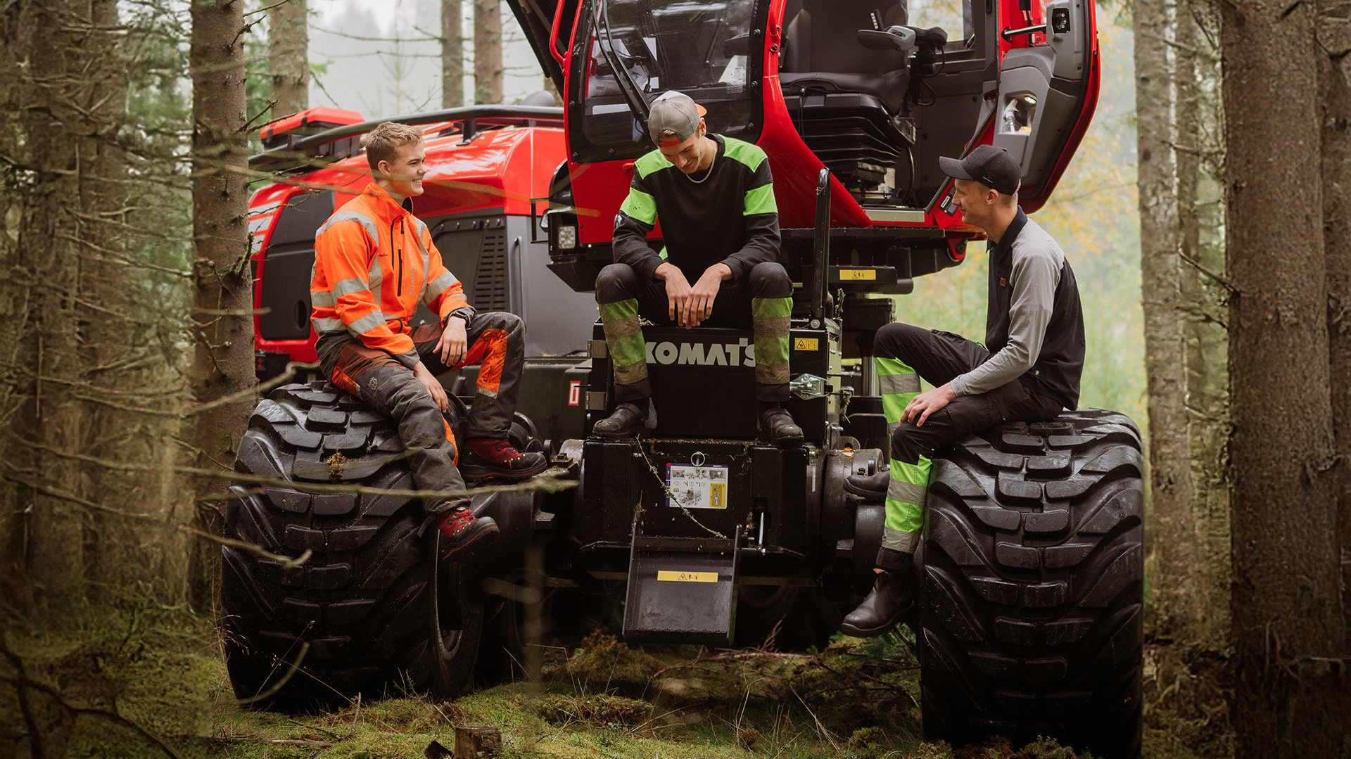 Three students are sitting and talking on a forestry machine in the forest