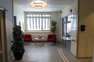 Reception bakom glaslucka till höger och sittplatser framför fönster i mitten