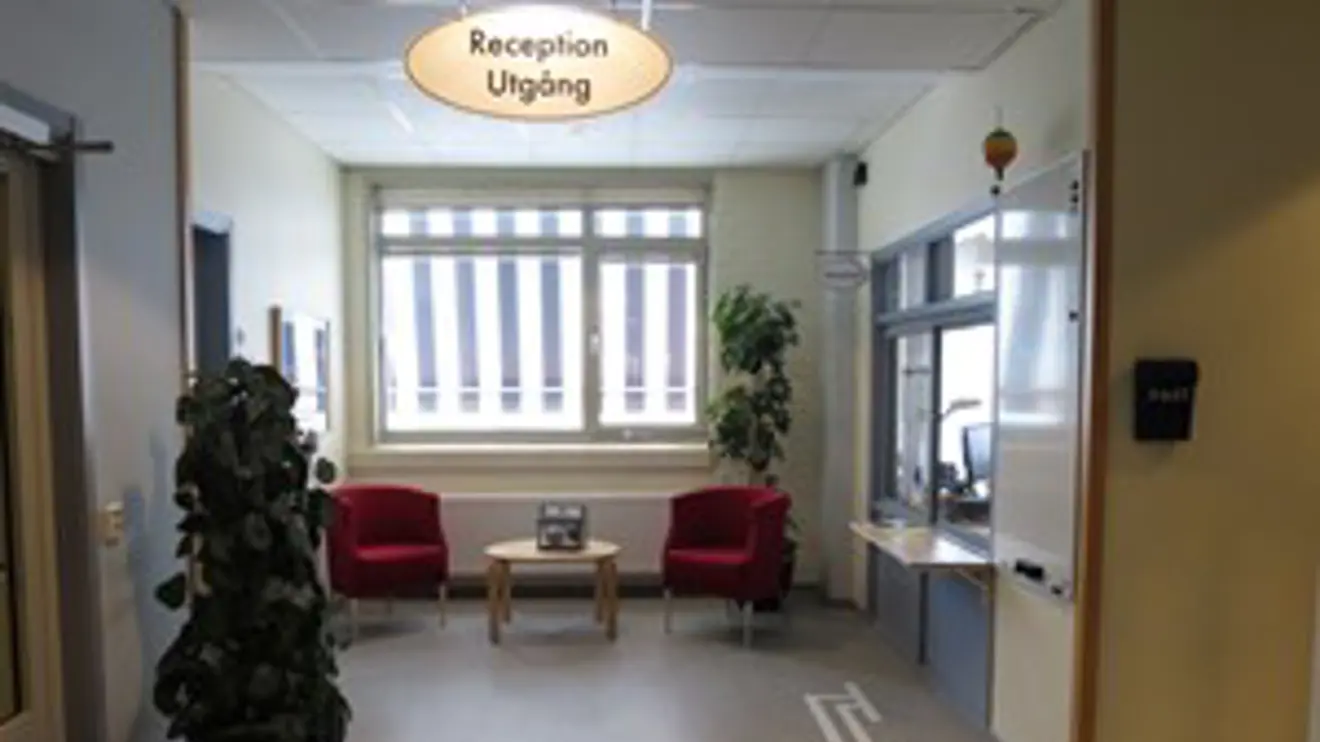 Reception bakom glaslucka till höger och sittplatser framför fönster i mitten