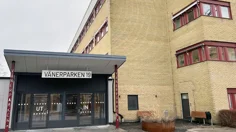 Glasad entré med tak till vänster om gul tegelbyggnad